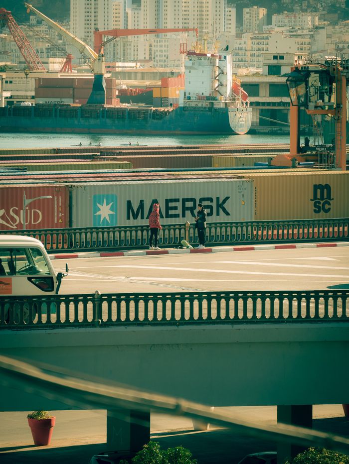 journey A vibrant harbor scene in Algiers with container ships and bustling activity, perfect for commercial use.