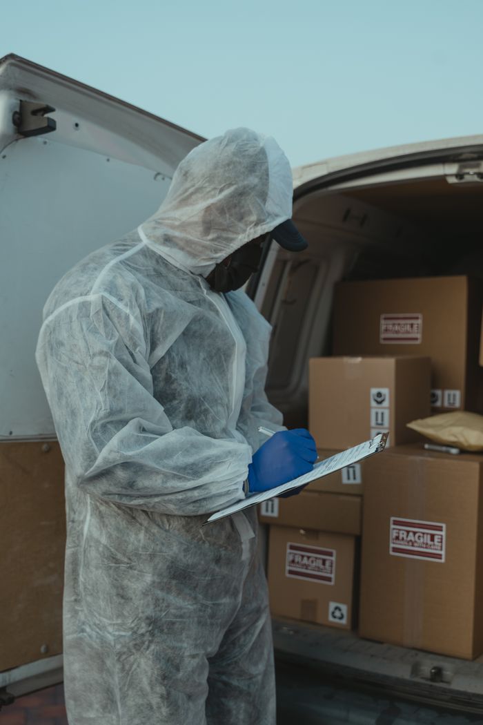 why-choose-us A logistics worker in PPE inspects packages in a delivery van for shipment.
